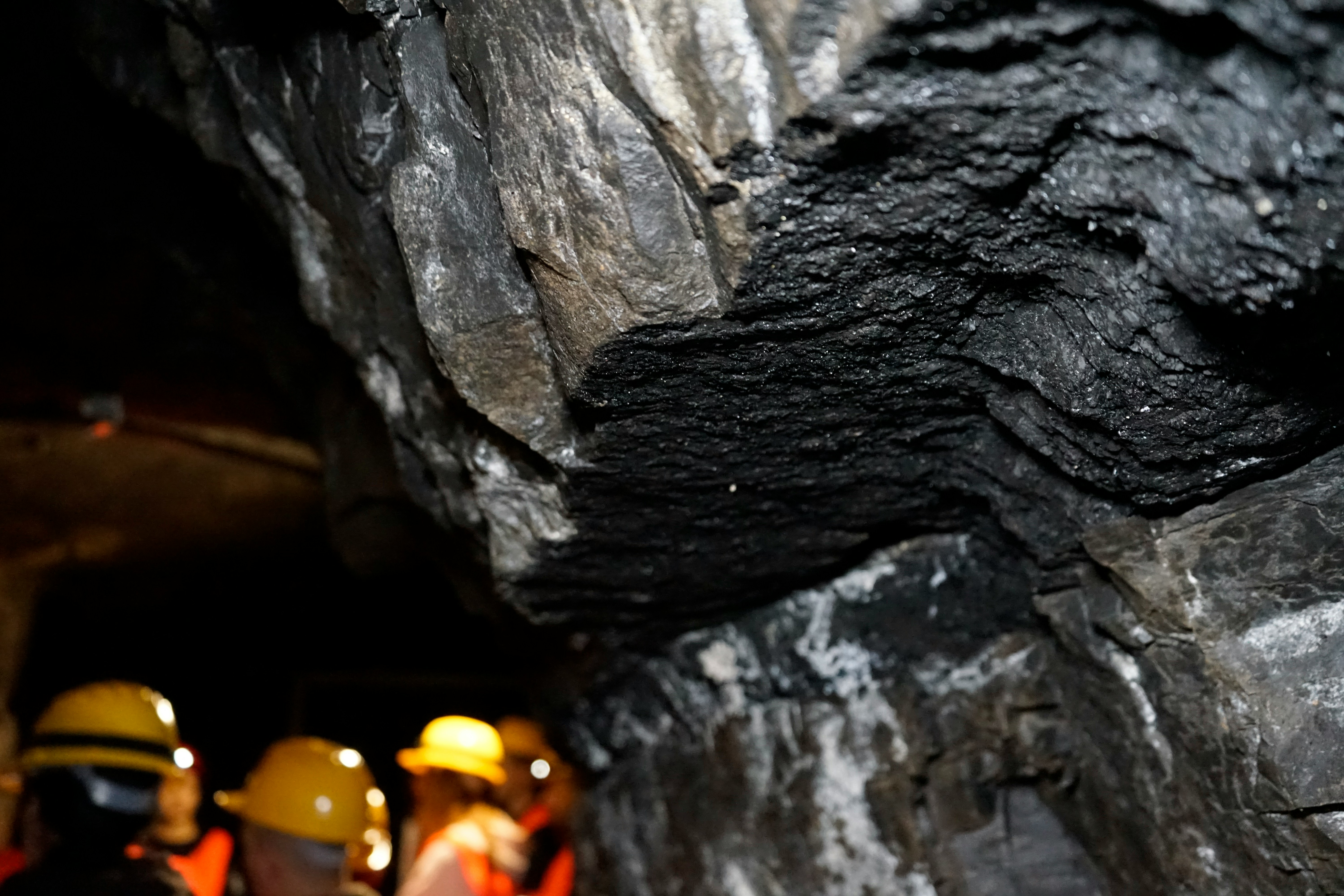 Helmeted miners inspecting a coal seam underground